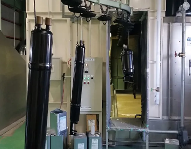 部品に黒い塗装を施して吊るしている様子