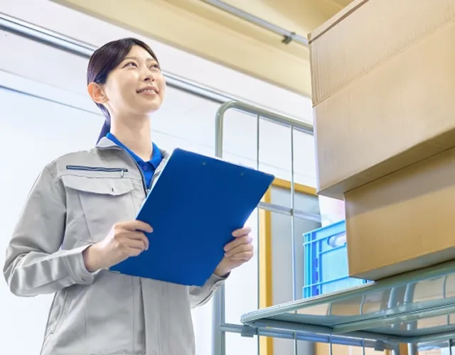 バインダーを持ち製品の仕上がりを笑顔で確認する女性担当者