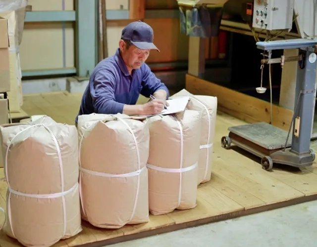 安全に梱包された完成品と納品準備をする作業員